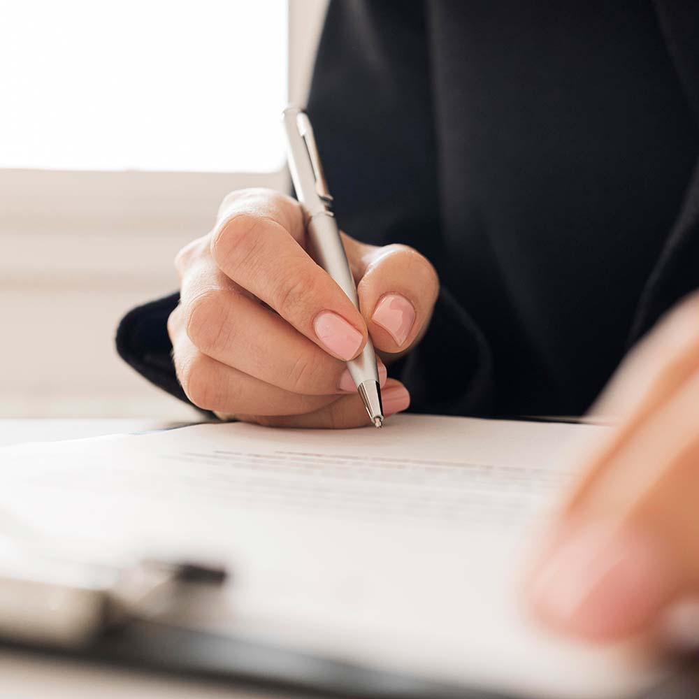 Mujer escribiendo en una hoja de papel.